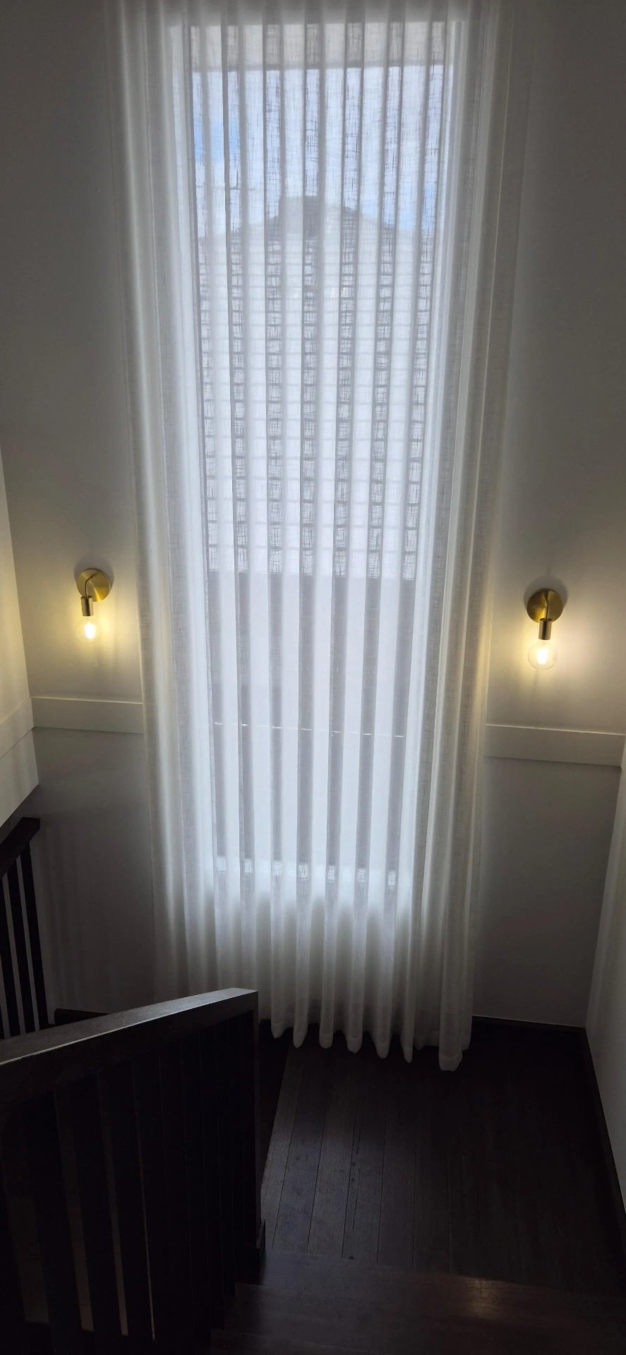 Pair of brass wall sconces in a tall stairwell
