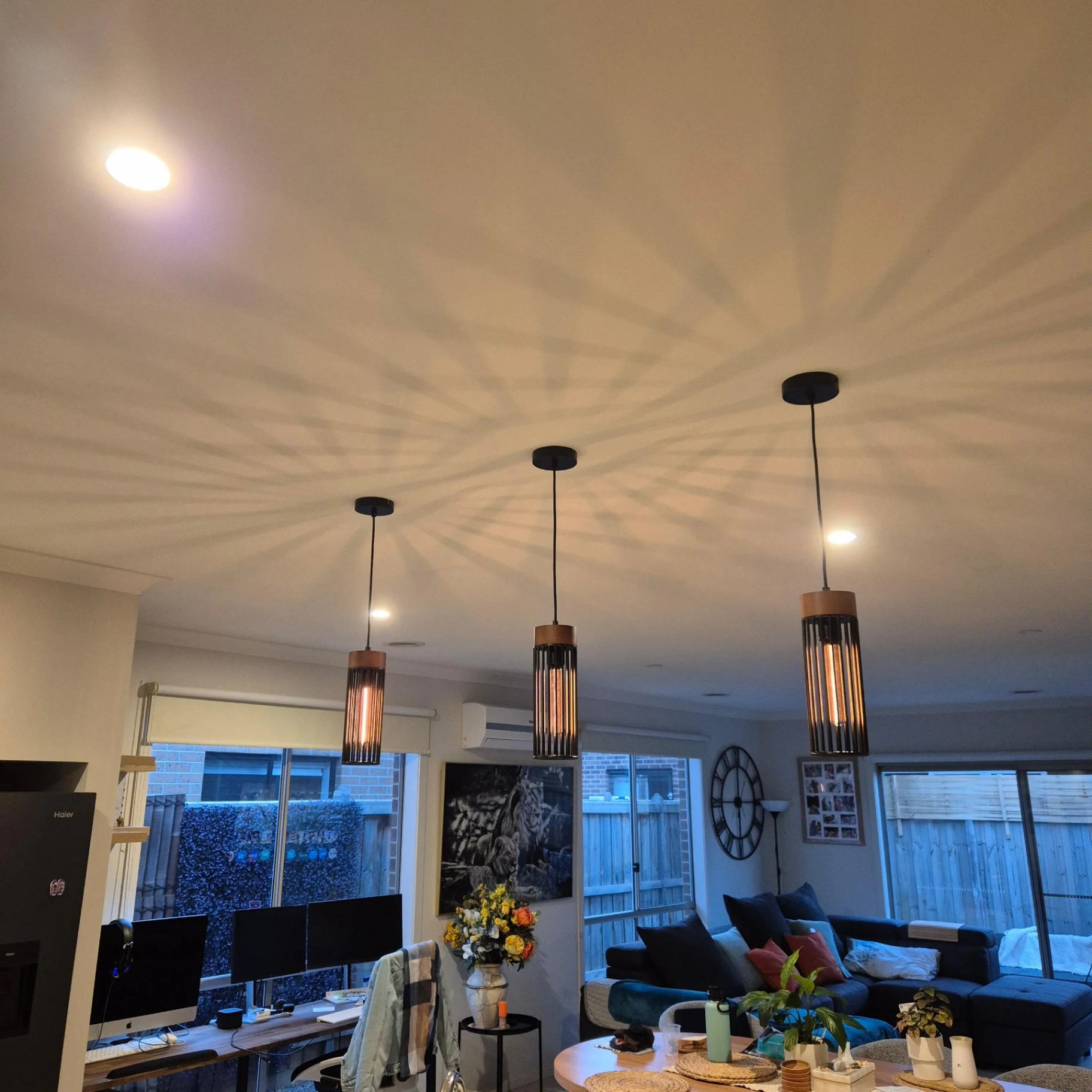 Trio of cage pendants over an open-plan dining area